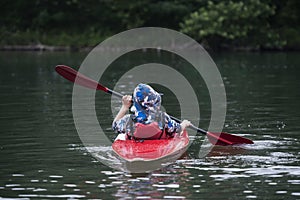 Boy teenager manages a canoe kayak on a wide river.