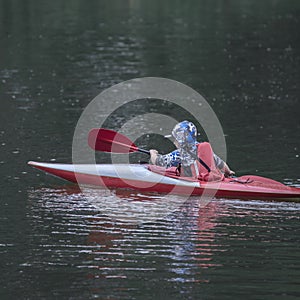 Boy teenager manages a canoe kayak on a wide river.