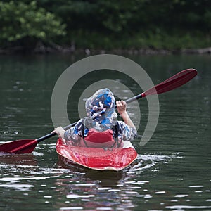 Boy teenager manages a canoe kayak on a wide river.