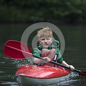 Boy teenager manages a canoe kayak on a wide river.