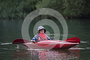 Boy teenager manages a canoe kayak on a wide river.