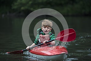 Boy teenager manages a canoe kayak on a wide river.