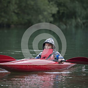 Boy teenager manages a canoe kayak on a wide river.