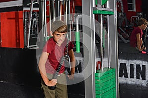 Boy teenager performs triceps exercise on the simulator in the gym. Health care from childhood