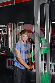 Boy teenager performs triceps exercise on the simulator in the gym. Health care from childhood