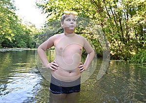 Boy teenager swims in river in summer