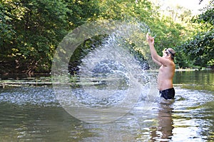 Boy teenager swims in river in summer