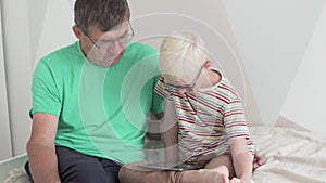 The boy is a teenager teaching his grandfather to use a tablet and the Internet