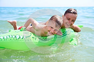 BOY OF TEENAGERS IN WATER GOGGLES SWIMS ON THE INFLATABLE TOY CROCODILE