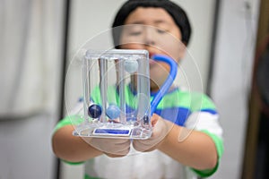 A boy is testing and administering lungs with a tri-ball dryer