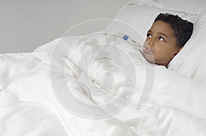 Boy With Thermometer Lying In Bed