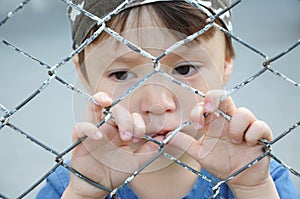 Boy thinking behind bars