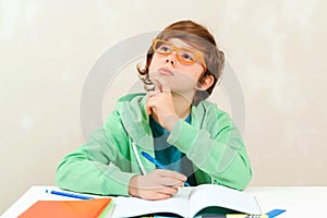 Boy thinking and doing homework. Little student boy studying and reading books