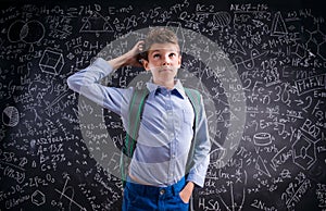 Boy thinking, scratching his head, blackboard with mathematical