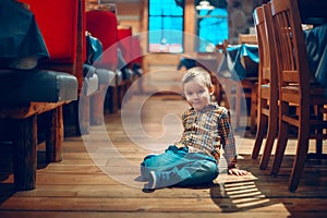 Boy three years old having fun in cafe restaurant. Child playing on floor in public place.