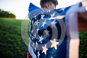 boy threw Flag of America on shoulders. flag of america USA at sunset outdoors. Independence Day. Constitution day