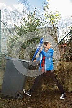 Boy throw Christmas tree in the Garbage bin roll trash container