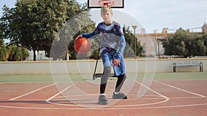 boy throwing ball on background of basketball court. Preadolescent child training basketball outside