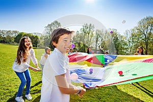 Boy throwing balls up by using rainbow parachute