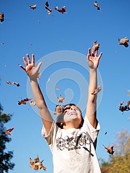 Boy throwing leaves in air