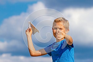 Boy throwing paper plane against blue sky