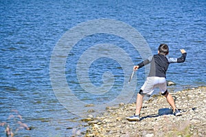 Boy Throwing Rocks into the Lake