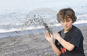 Boy throwing shingle on beach