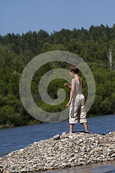 Boy throwing stone in lake