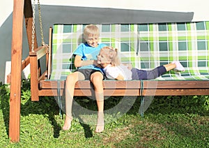 Boy tickling girl on a wooden swing