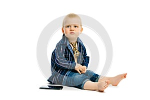 Boy in a tie sitting on a white floor