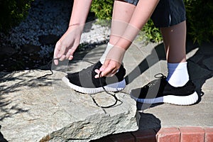 The boy ties the laces on athletic shoes