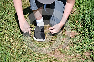 The boy ties the laces on athletic shoes