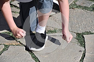 The boy ties the laces on athletic shoes