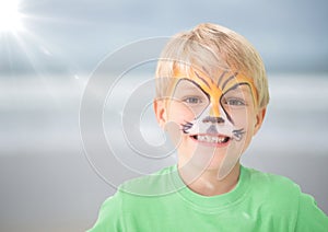 Boy with tiger facepaint against blurry beach with flare