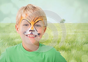 Boy with tiger facepaint against meadow with flare