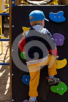 boy toddler on the outdoor climbing wall in the playground