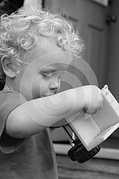 Boy toddler plays with truck outside his front door.