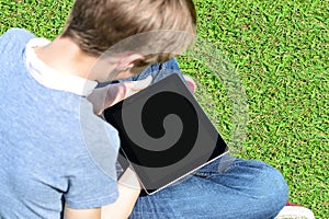 Boy with touch pad sitting on meadow