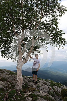 Boy touching birch on Lago-Naki plateau in summer