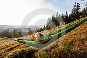 Boy tourist resting in a hammock in the mountains at sunset