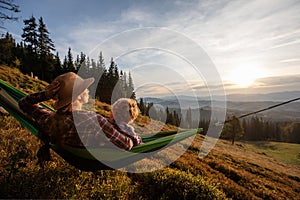 Boy tourist resting in a hammock in the mountains at sunset