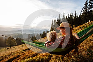 Boy tourist resting in a hammock in the mountains at sunset