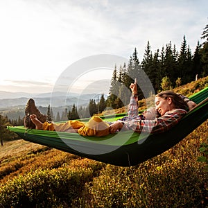 Boy tourist resting in a hammock in the mountains at sunset