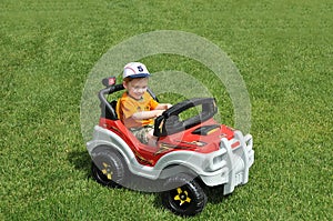 Boy in toy car on grass