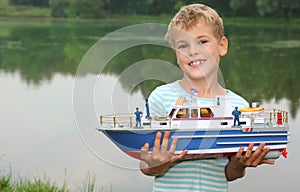 Boy with toy ship in hands ashore