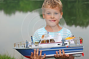 Boy with toy ship in hands ashore