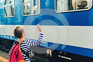 Boy on the train station wave goodbye. Kid with backpack on a subway