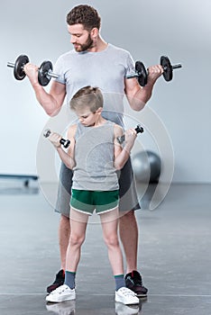 Boy training with dumbbells together with coach