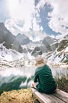 Boy traveler rests near beautiful mountain lake. Spring summer h