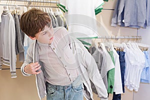 The boy tries on clothes in store